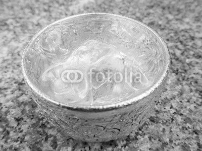 Aluminum bowl with water and  ice cube on the dining table in the restaurant, Thai style