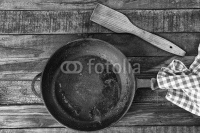 Large empty black cast iron pan on a brown wooden surface