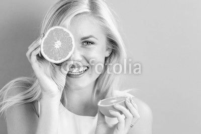 Happy young woman holding orange halves