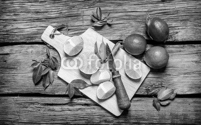 Sliced limes on a wooden board with leaves and knife.