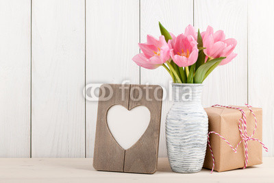 Fresh pink tulips, blank frame and gift box