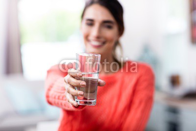 Young woman showing drinking glass with water
