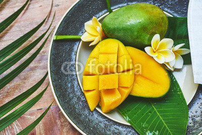 Fresh mango on a wooden tabel with tropical background. Soft focus.
