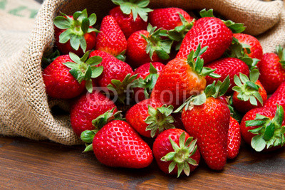 fresh strawberry in burlap sack on wood
