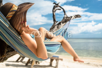 Frau im Urlaub am Strand entspannt in Hängematte am Meer