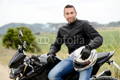 handsome young man biker with white helmet riding black motorcycle