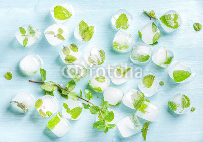 Ice cubes with frozen mint leaves inside on blue Turquoise background