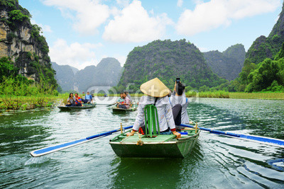 Tourists in boats. Rowers using feet to propel oars, Vietnam