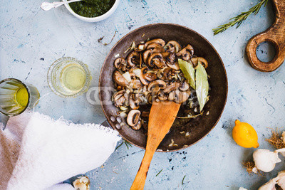 Fried mushrooms cast-iron pan on table.