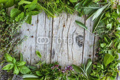 Fresh and aromatic herbs in frame on old wooden table. Space for text. 