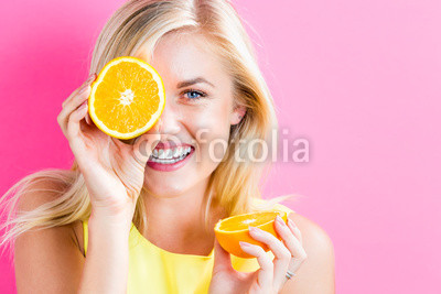 Happy young woman holding orange halves