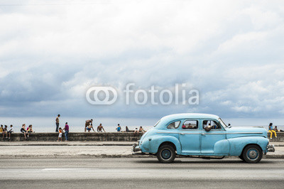HAVANA, CUBA - MAY 18, 2011: Classic vintage American car serving as taxi drives along the seafront Malecon, a popular place for socializing in Central Havana.