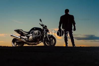 Silhouette of man in leather outfit with motorbike