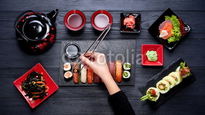 Woman eating sushi with chopsticks top view