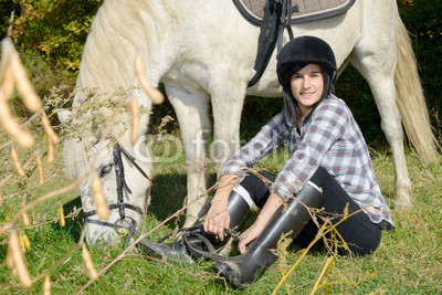 Portrait of a pretty young woman with white horse riding