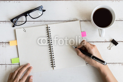 Cup of coffee with notebook and copy space on white wooden desk