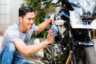 Asian man washing his motorcycle or scooter