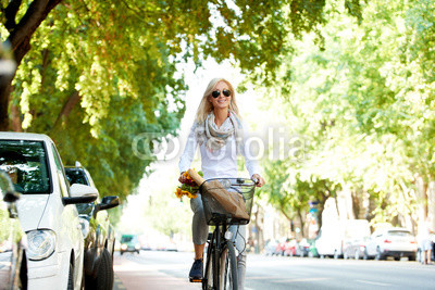 She goes everywhere by bike. Full length shot of a young woman in the street with a bicycle.