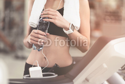 Slim woman holding a bottle after workout