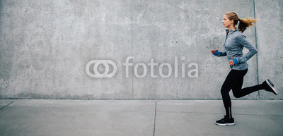 Young woman running on sidewalk in morning