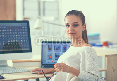 Young woman working in office, sitting at desk