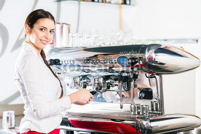 Young waitress using an automatic coffee machine