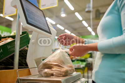 woman weighing potatoes on scale at grocery store