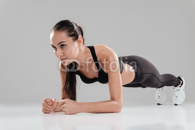 Focused beautiful young sportswoman working out and doing plank