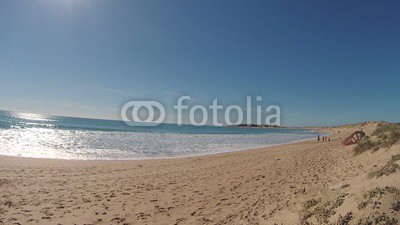 Unrecognizable people on the beach, with the Trafalgar lighthouse in the background, on the coast of Cadiz, Spain