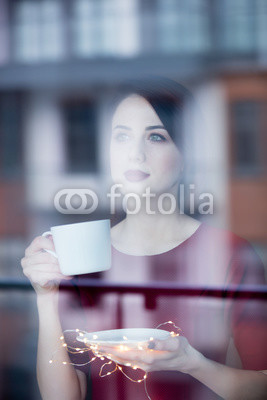 Beautiful redhead woman with cup of coffee or cappuccino near a