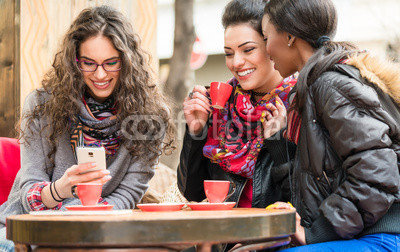 Women in cafe showing pictures on smart phone