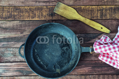 Large empty black cast iron pan on a brown wooden surface