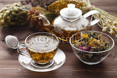 medicinal tea in glass cup with dried herb in bowl