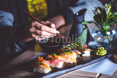 Man eating sushi set with chopsticks on restaurant