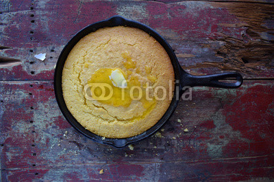 Yellow Cornbread in cast iron skillet on rustic wood table
