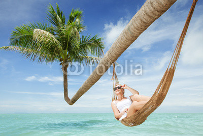 view of nice young lady swinging  in hummock on tropical beach