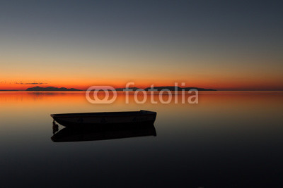 A warm sunset on a calm water, with Islands in the background