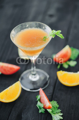 coctail with orange and tomato on black wooden table at blurred background