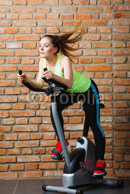 Active woman using exercise bike at the gym.