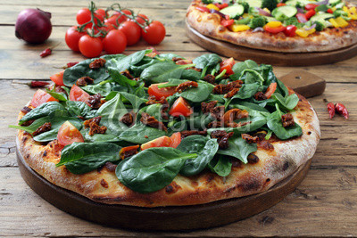 pizza vegetariana con spinaci e pomodori freschi su sfondo rustico