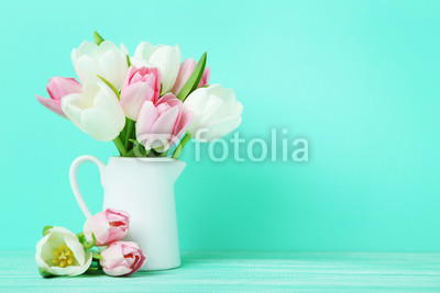 Bouquet of tulips in jug on green background