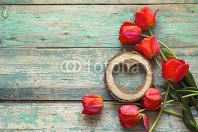 Background with red tulips and wooden hearts on old wooden boards.