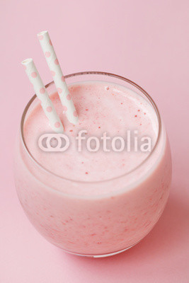 Strawberry pink smoothie in a glass with a straw on a pink background. Summer and healthy lifestyle concept.