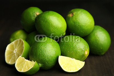 Fresh juicy limes on wooden table, on dark background