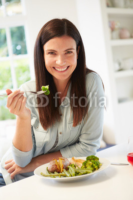 Portrait Of Woman Eating Healthy Meal In Kitchen