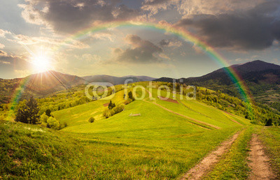 fence on hillside meadow in mountain at sunset