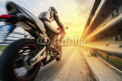 Moto da strada sfreccia vicino al guard rail al tramonto