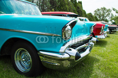 Vintage hot rods at a car show front ends. A row of awesome hot rods at a car show restored front ends with headlights exposed engines and grilles. Row of cars at a car show.