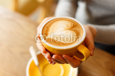 lady's hands holding cup with sth heart-shaped