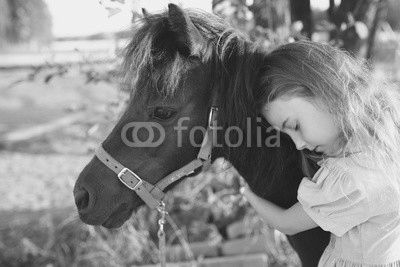 Young girl hugs a pony on a farm